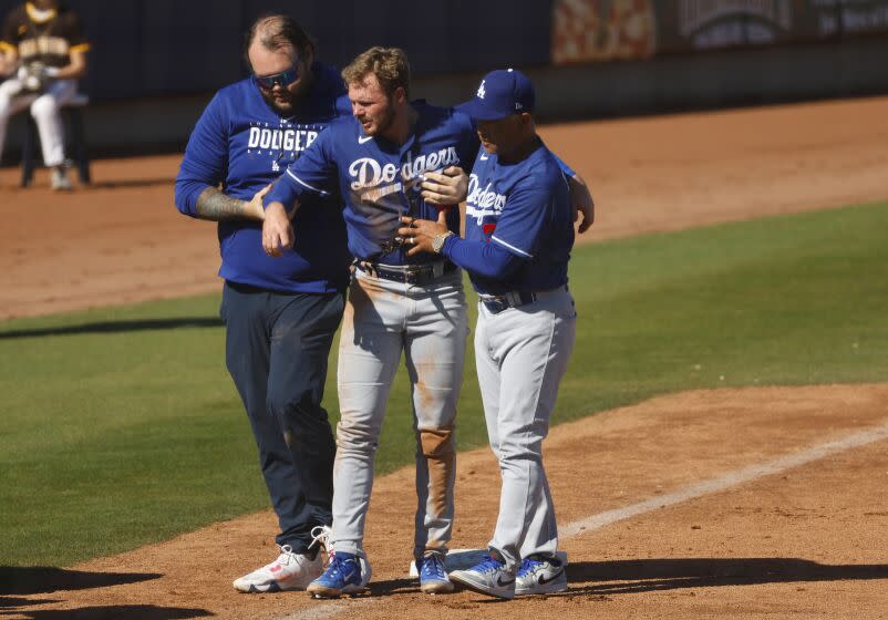 Peoria AZ - February 27: Los Angeles Dodgers' Gavin Lux is loaded onto a cart with the help of a trainer.