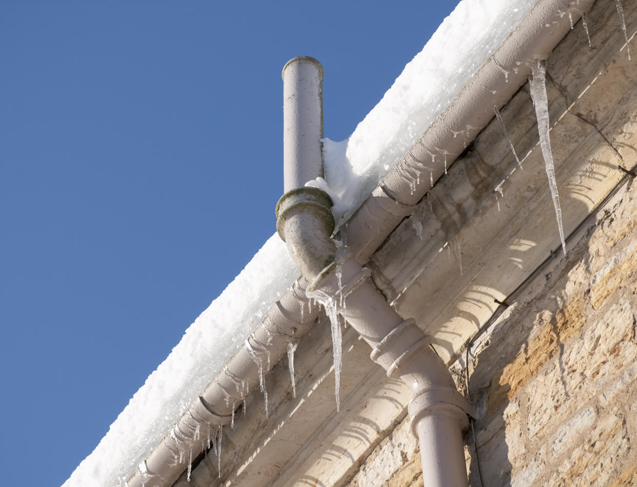 cold weather Icicles hanging from the gutter, and snow on the roof causing drainage problems for an old building in winter.