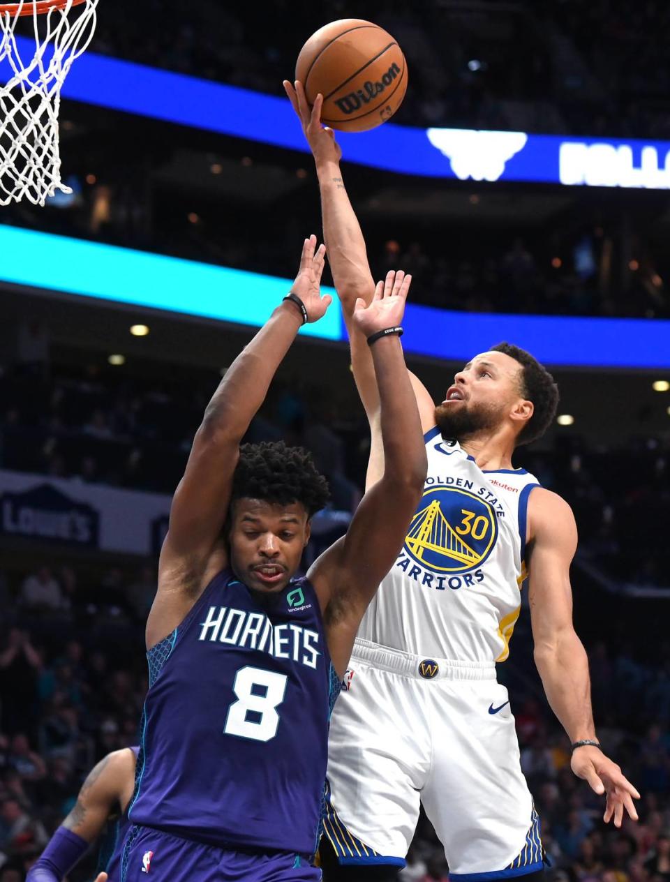 Golden State Warriors guard Stephen Curry, right, releases a running one-handed shot in the lane over Charlotte Hornets guard Dennis Smith Jr., left, during second half action at Spectrum Center on Saturday, October 29, 2022. The Hornets defeated the Warriors 120-113.