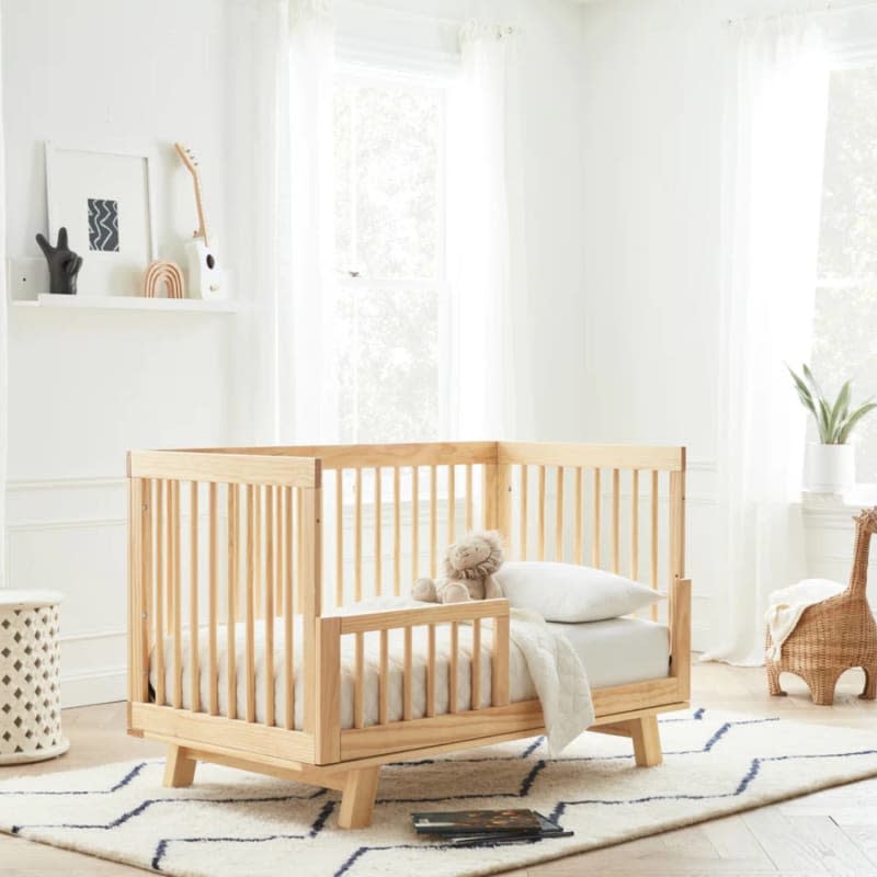 Light natural wood crib with thick angled legs in neutral nursery