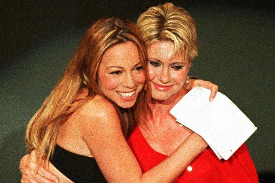 Pop music diva Mariah Carey(L) hugs singer-actress Olivia Newton John(R) who presented Carey with a special award during the 27th Annual American Music Awards 17 January 2000 in Los Angeles. Carey is only the third recipient of the "Award of Achievement" in the show's history, joining Michael Jackson and Prince.