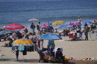 Familes enjoy the hot weather on Santa Monica Beach in Santa Monica, Calif., Wednesday, March 31, 2021. Half of the state's nearly 40 million people are now in the state's second-least restrictive orange tier amid low coronavirus case rates and increased vaccinations. Health officials in California and across the country are urging caution because of a troubling rise in new cases of COVID-19. (AP Photo/Damian Dovarganes)