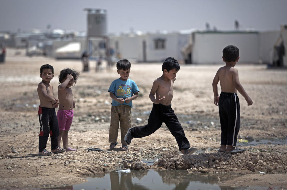 In this Thursday April 17, 2014 photo, Syrian children play under the heat of the midday sun at Zaatari refugee camp, near the Syrian border in Jordan. Life in this sprawling camp, Zaatari, is only getting harder for 130,000 residents, most of them fleeing fighting in south Syria. (AP Photo/Khalil Hamra)