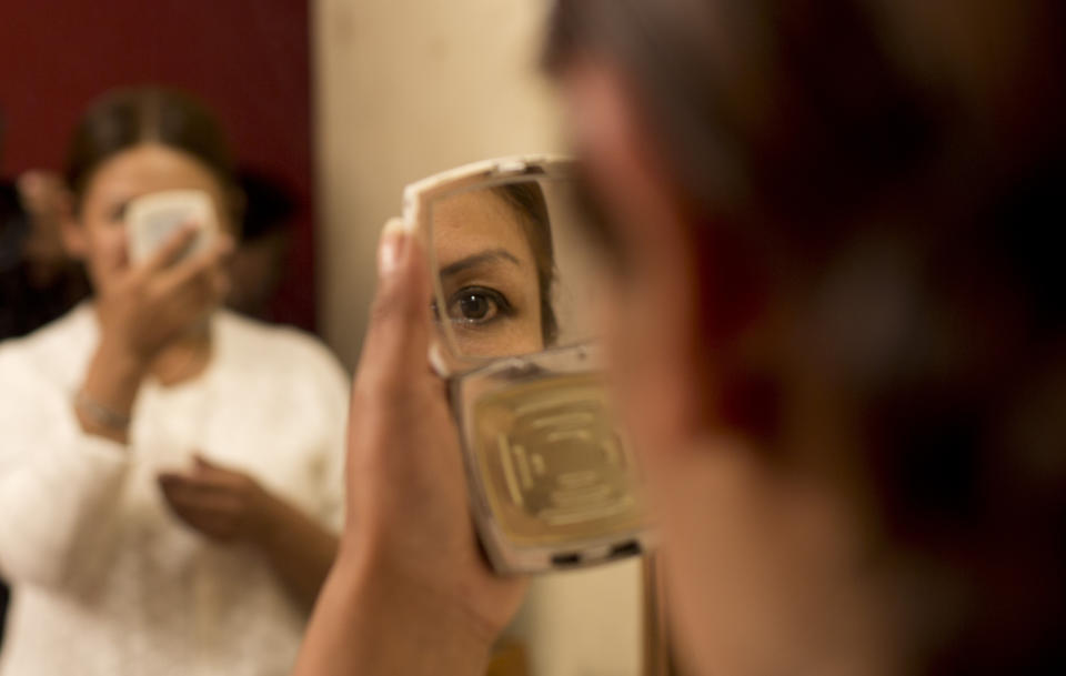 En esta imagen del 30 de abril de 2019, una integrante de la compañía de teatro "Kory Warmis", o Mujeres de oro, se mira en un espejo pequeño mientras espera a actuar en el Teatro Municipal de La Paz, Bolivia. (AP Foto/Juan Karita)