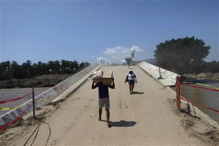 People walk on a collapsed bridge in Coyuca de Benitez on the outskirts of Acapulco, October 2, 2013. REUTERS/Edgard Garrido