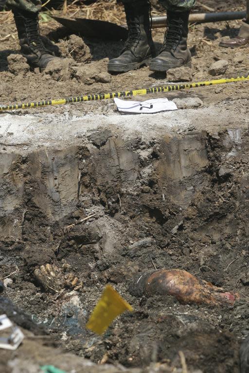 Soldiers stand guard next to parts of a corpse that in a grave in Tunzingo, Guerrero state, on November 3, 2010