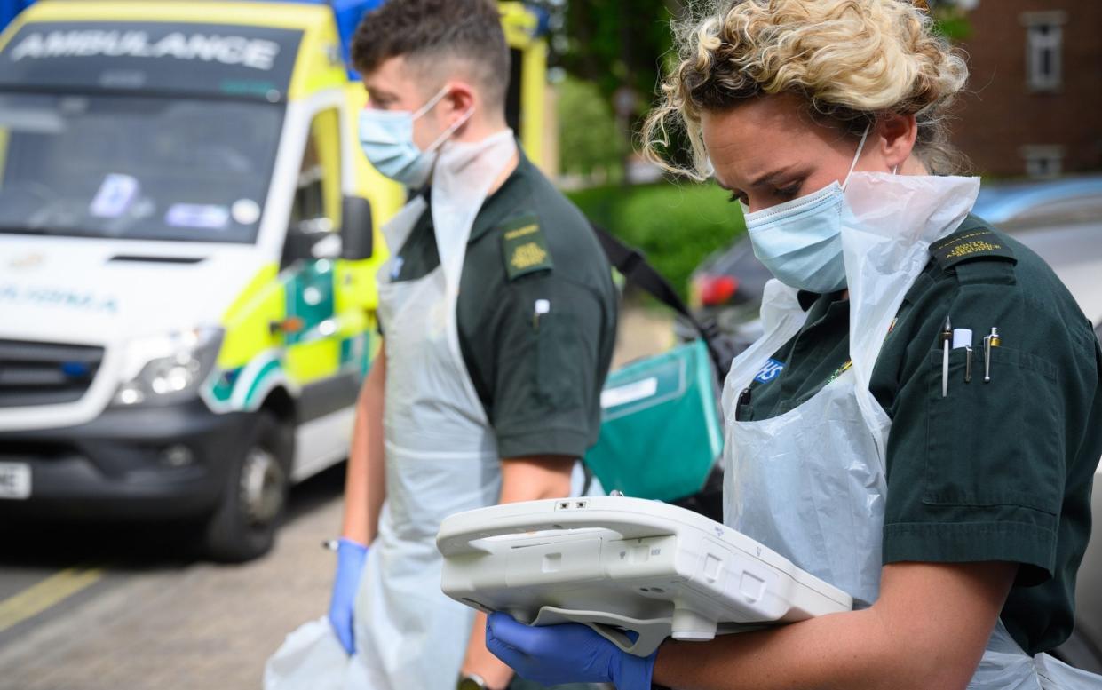 PORTSMOUTH, ENGLAND - MAY 05: An ambulance crew from the South Central Ambulance Service wear protective clothing as they complete the digital paperwork after responding to a false alarm call for a heart attack on May 05, 2020 in Portsmouth, England. Due to the risk of contamination to the air ambulance helicopters, patients have been transferred to the mainland using the hovercraft service since the beginning of May. As the list of recognised Covid-19 symptoms grows, paramedic crews like those with the South Central Ambulance Service are forced to treat every patient as being a potential case, often requiring specialised personal protective equipment (PPE). Paramedics now routinely don what the NHS refers to as Level 2 PPE, like face masks and disposable aprons. Cases with patients potentially needing airway procedures require Level 3 PPE, such as full-face visors and long-sleeved surgical gowns. While the infection rate is falling, and government officials are discussing ways to relax the country's quarantine measures, Covid-19 still creates everyday risks for paramedics and other first responders. (Photo by Leon Neal - Pool/Getty Images)  - Leon Neal/Getty Images