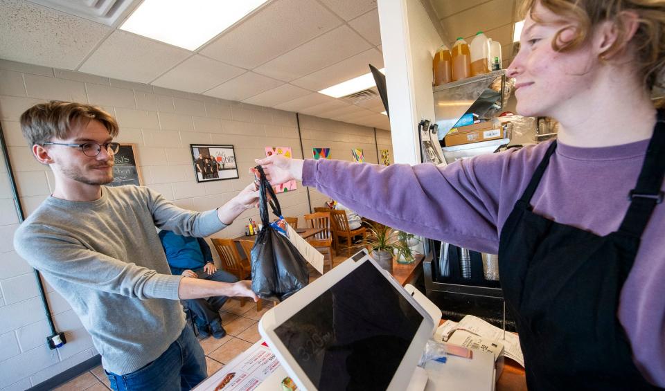 Riley Seddon hands over an order Driver On Deck's Ashton Hersherger at Chef's Table Catering on Wednesday, March 21, 2024.