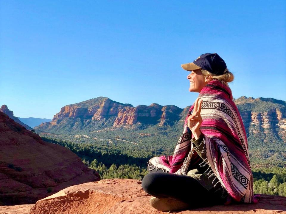 The writer sitting on orange rock in surrounded by natural landscape in arizona