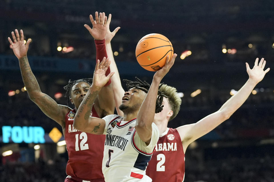 UConn guard Stephon Castle (5) drives to the basket between Alabama guard Latrell Wrightsell Jr. (12) and forward Grant Nelson (2) during the second half of the NCAA college basketball game at the Final Four, Saturday, April 6, 2024, in Glendale, Ariz. (AP Photo/David J. Phillip)