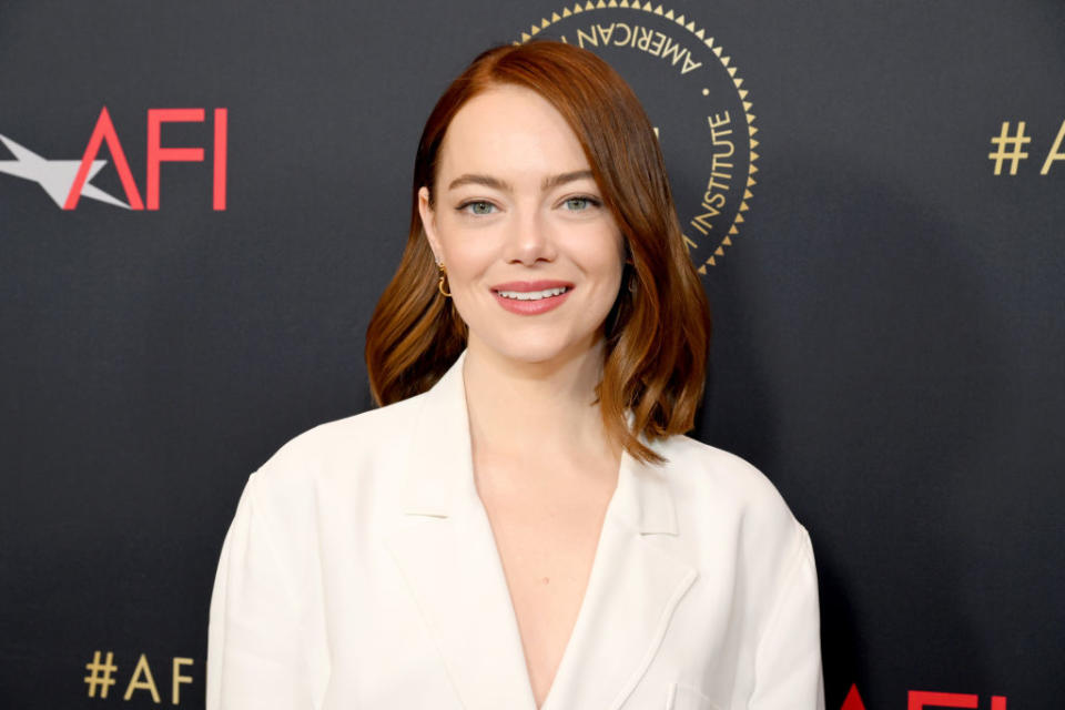 Emma Stone poses in a white blazer at an AFI event