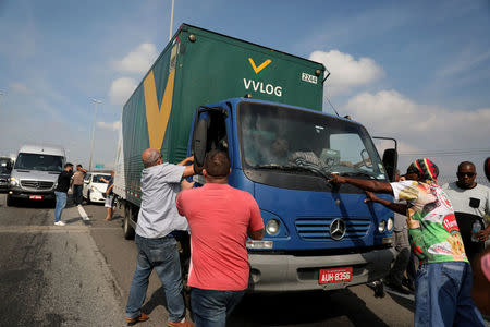 Truckers try to stop another truck driver who doesn't want to protest against high diesel fuel prices in Duque de Caxias in Rio de Janeiro, Brazil May 24, 2018. REUTERS/Pilar Olivares