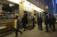 Police surround a bar which they have raided and whose owner they have arrested for operating illegally in defiance of pandemic restrictions in Warsaw, Poland, Friday March 26, 2021. A raft of new pandemic restrictions take effect in Poland on Saturday to slow the spread of infection in what has become of the new global hot spot for the virus, but even earlier restrictions are being defied by some.(AP Photo/Czarek Sokolowski)