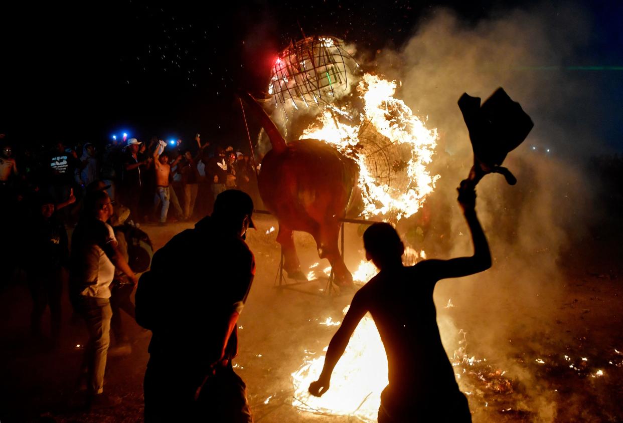 People take shelter while others run around a traditional "torito" (little bull), a frame for fireworks made of paper mache, reed, wood and wires in the form of a bull, during celebrations of San Juan de Dios held in the framework of the National Pyrotechnic Festival, in Tultepec, Mexico State, Mexico, on March 8, 2023.