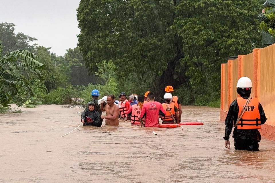 Rescuers help residents as they negotiate floods caused by powerful Typhoon Krathon locally called ‘Typhoon Julian’ at Bacarra, Ilocos Norte province, northern Philippines (AP)