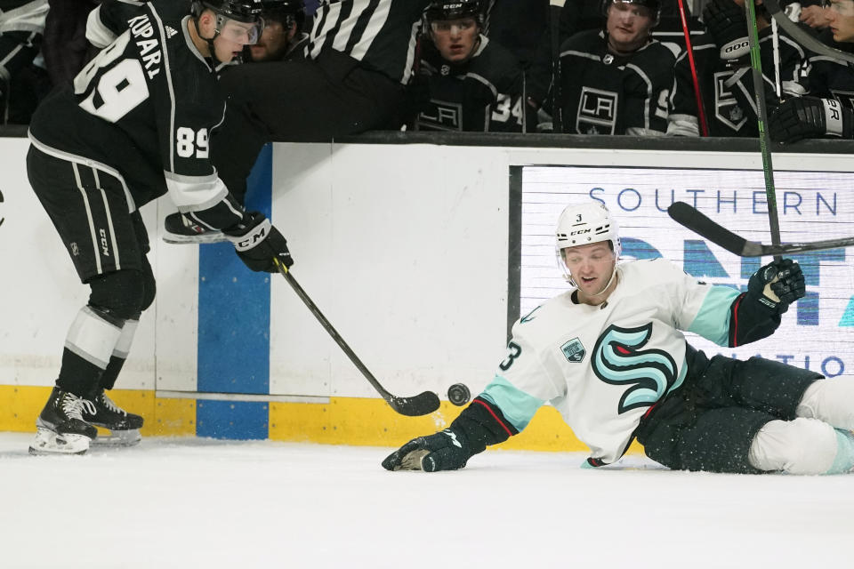 Los Angeles Kings center Rasmus Kupari, left, passes the puck as Seattle Kraken defenseman Will Borgen falls during the second period of an NHL hockey game Monday, March 28, 2022, in Los Angeles. (AP Photo/Mark J. Terrill)