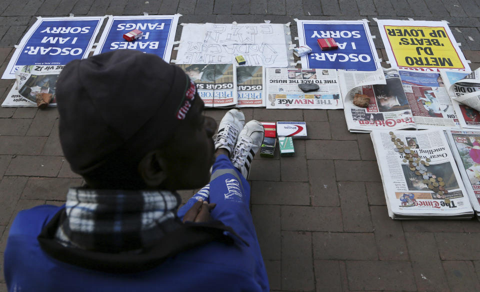 A vendor sells newspaper with headlines on Oscar Pistorius ouside the high court in Pretoria, South Africa, Tuesday, April 8, 2014. Pistorius, who is charged with murder for the shooting death of his girlfriend, Reeva Steenkamp, on Valentines Day in 2013, was testifying for a second day at his murder trial Tuesday, answering questions from his defense lawyer. (AP Photo/Themba Hadebe)