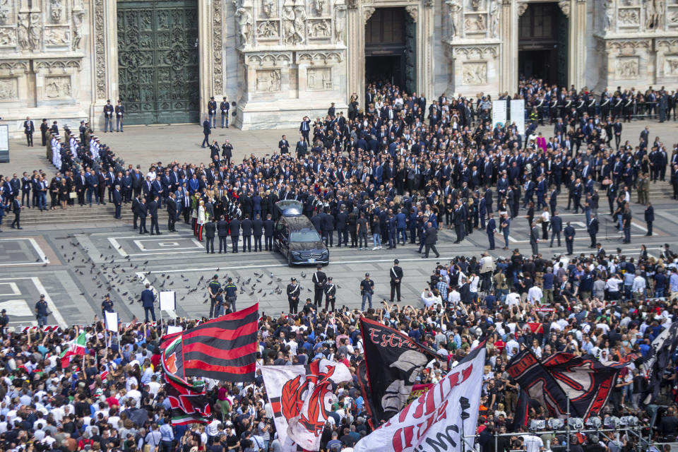 AC Milan flags wave in the crowd as the hearse carrying his former Italian premier Silvio Berlusconi's casket prepares to leave at the end of his state funeral in Milan's Duomo Gothic-era Cathedral, Italy, Wednesday, June 14, 2023. Berlusconi died at the age of 86 on Monday in a Milan hospital where he was being treated for chronic leukemia. (Stefano Porta/LaPresse via AP)