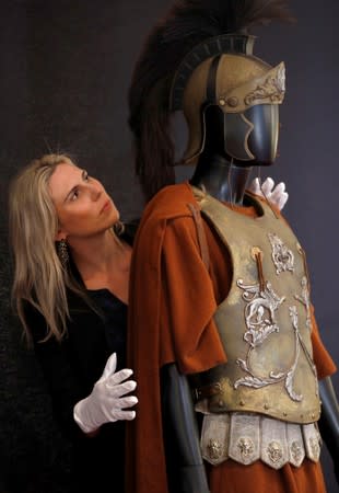An employee of Prop Store poses for a photograph with Russell Crowe's "Maximus" Roman general armour from the film "Gladiator", at a preview of a film and tv memorabilia sale in London