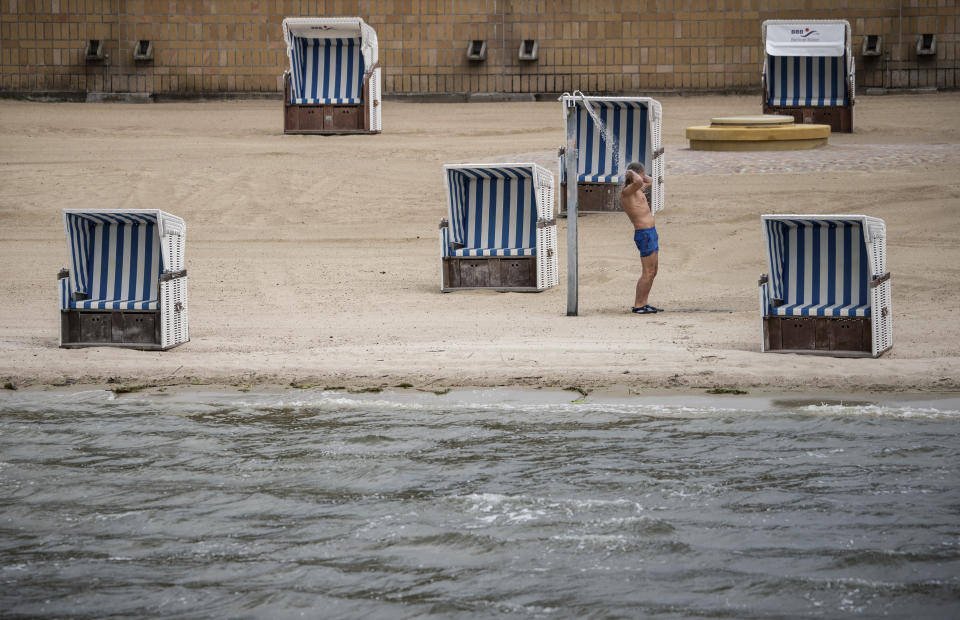 A man take a shower in front of empty beach chairs at the Strandbad Wannsee a public swimming area at the Wannensee lake in Berlin, Germany, May 25, 2020. Berlin's open-air swimming pools reopen after the lockdown because of the coronavirus crisis. In future, 400 guests will be allowed to enter the lido in the morning and in the afternoon again, subject to safety distances and prior notification. (Michael Kappeler/dpa via AP)