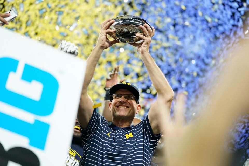 Michigan head coach Jim Harbaugh holds the trophy after defeating Purdue in the Big Ten championship NCAA college football game, early Sunday, Dec. 4, 2022, in Indianapolis. Michigan won, 43-22. (AP Photo/Michael Conroy)