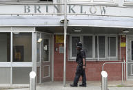 A police officer outside Brinklow Tower in Birmingham, England, where searches have been carried out in relation to the suspected terror attack on the Houses of Parliament in London, Wednesday Aug. 15, 2018. This search is believed to be linked to a car that crashed into security barriers outside the Houses of Parliament in London, Tuesday, and the driver was taken into custody. (Aaron Chown/PA via AP)