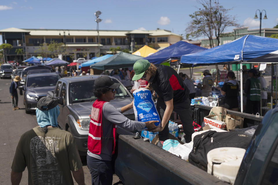 Volunteers work at a food distribution center set up in the parking lot of a shopping mall in Lahaina, Hawaii, Wednesday, Aug. 16, 2023, after wildfires devastated parts of the Hawaiian island of Maui. (AP Photo/Jae C. Hong)