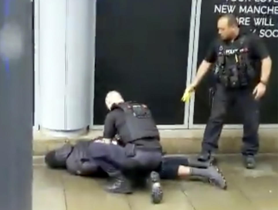 In this image taken from mobile phone footage, police arrest a man outside the Arndale Centre in Manchester, England, Friday October 11, 2019, after a stabbing incident at the shopping center that left four people injured. Greater Manchester Police say a man in his 40s has been arrested on suspicion of serious assault. He has been taken into custody. (John Greenhalgh via AP)