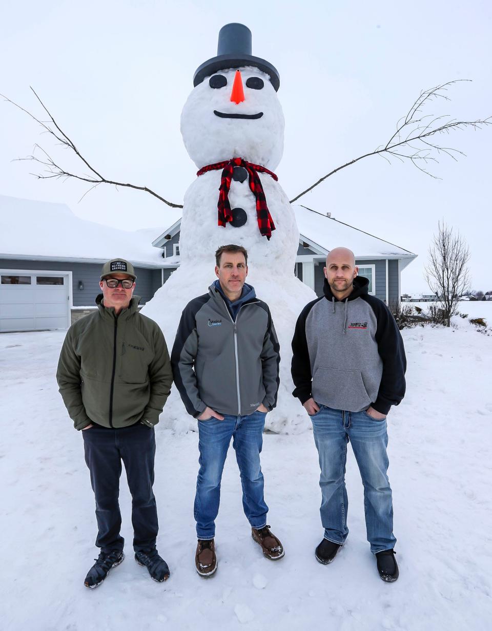 Nate Altheimer, of Belgium, Wis., left, Jon Voskuil, middle, and Michael Voskuil, right, stand in front of their 18-foot-tall Mr. Frosty, Monday, January 22, 2024, in Cedar Grove, Wis., The builders, working with Children’s Wisconsin, hope to raise charitable funds for the organization.