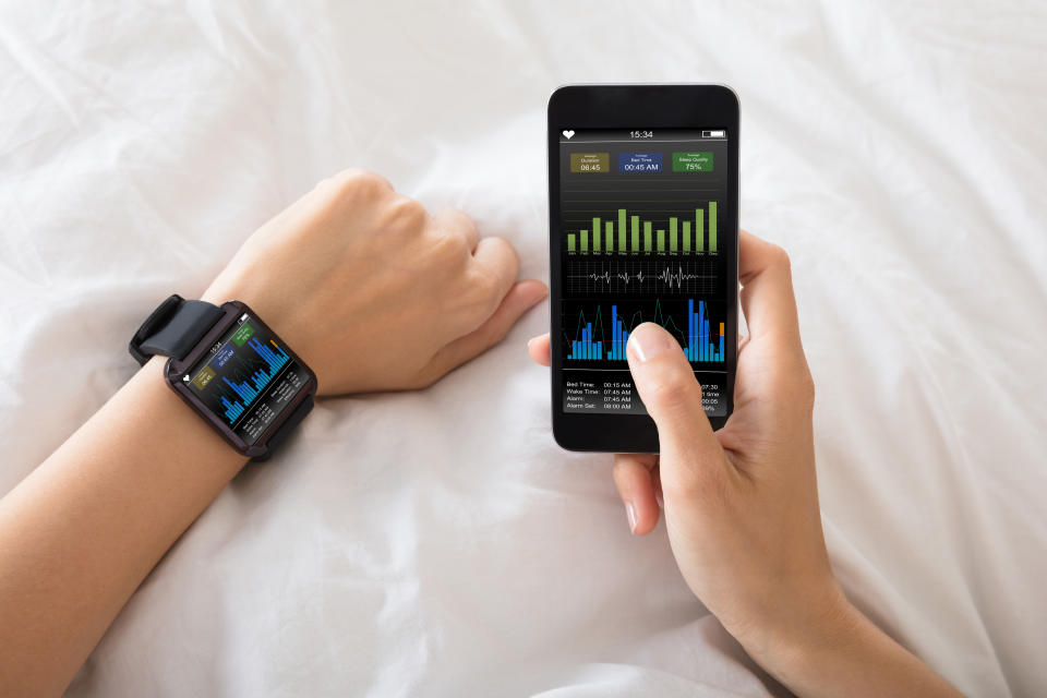 Person wearing a smartwatch while checking health tracking data on a smartphone