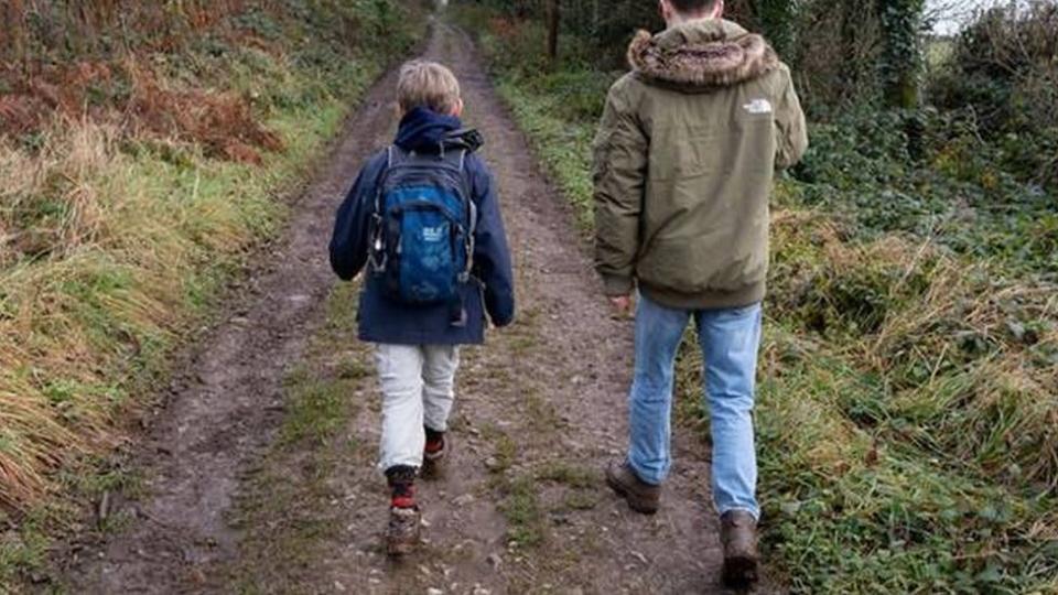 Pai e filho caminhando por trilha