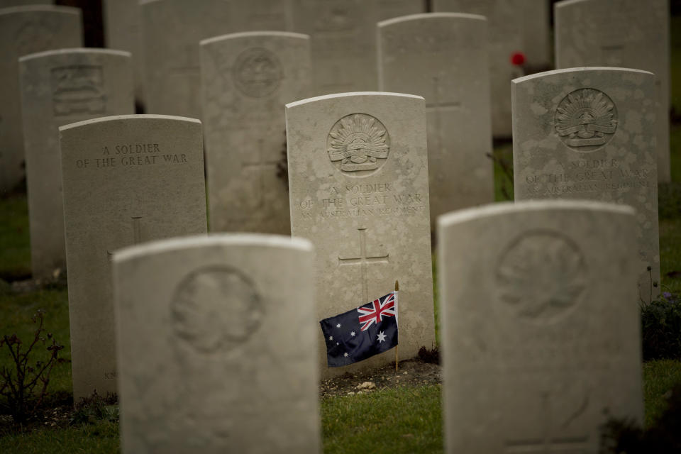 An Australian flag adorns the headstone of an unknown soldier at the World War I Australian National Memorial in Villers-Bretonneux, France, Saturday, Nov. 10, 2018. The memorial walls at the site bear the names of 11,000 missing Australian soldiers who died in France during World War I. (AP Photo/Francisco Seco)