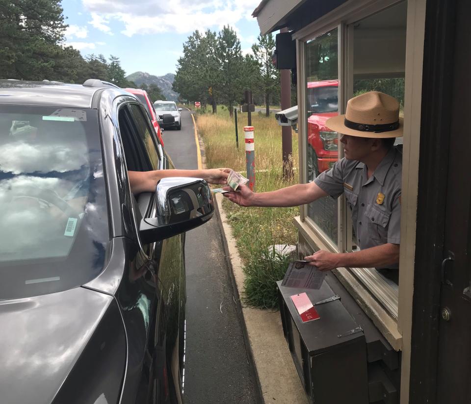 A Rocky Mountain National Park ranger takes money from a visitor at the Fall River entrance on Sept. 18, 2019. The Fall River entrance station's major renovation was expected to be finished by late June but completion has been moved to late fall. The entrance is one of Rocky Mountain National Park's busiest entrance stations.