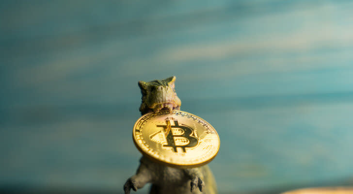 Dinosaur figurine holding a Bitcoin (BTC) concept coin between its teeth