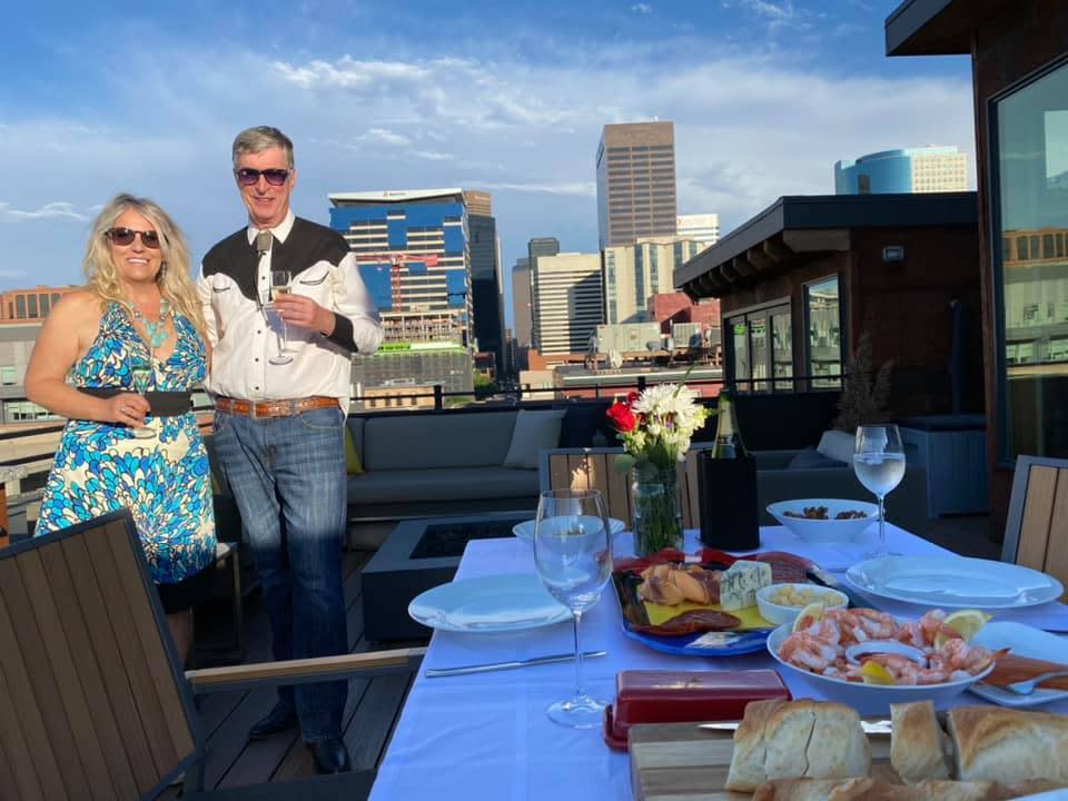This July 3, 2020 image provided by Peter Batty shows him and his wife celebrating their anniversary and the opening night of the Santa Fe Opera on their balcony in Denver, Colorado. The famed opera is offering a series of virtual performances after being forced to cancel the 2020 season due to the coronavirus pandemic. The Saturday night events are meant to celebrate the five originally-scheduled operas that would have been performed this summer. (Peter Batty via AP)