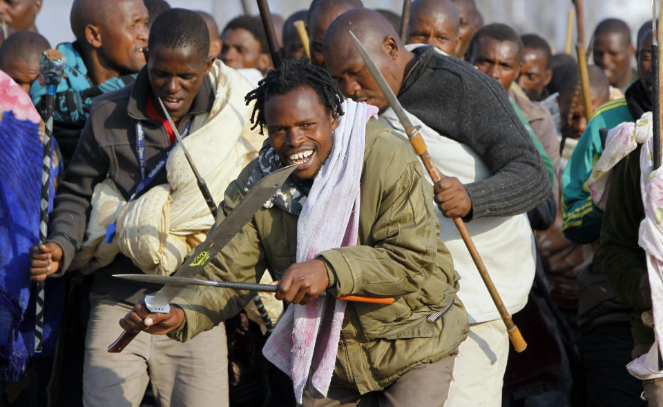 Striking miners sing, chant, march and dance with crudely made weapons and machetes at the Lonmin mine near Rustenburg, South Africa, Wednesday Aug. 15, 2012. Ongoing violence that started last Friday has seen 10 people killed, with no end to the strike in sight. (AP Photo/Denis Farrell)