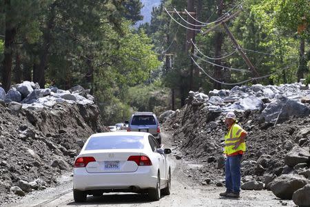 Vehicles pass through an area damaged by a mudflow triggered by flash floods in the San Bernardino National Forest community of Forest Falls, California August 4, 2014. REUTERS/Jonathan Alcorn