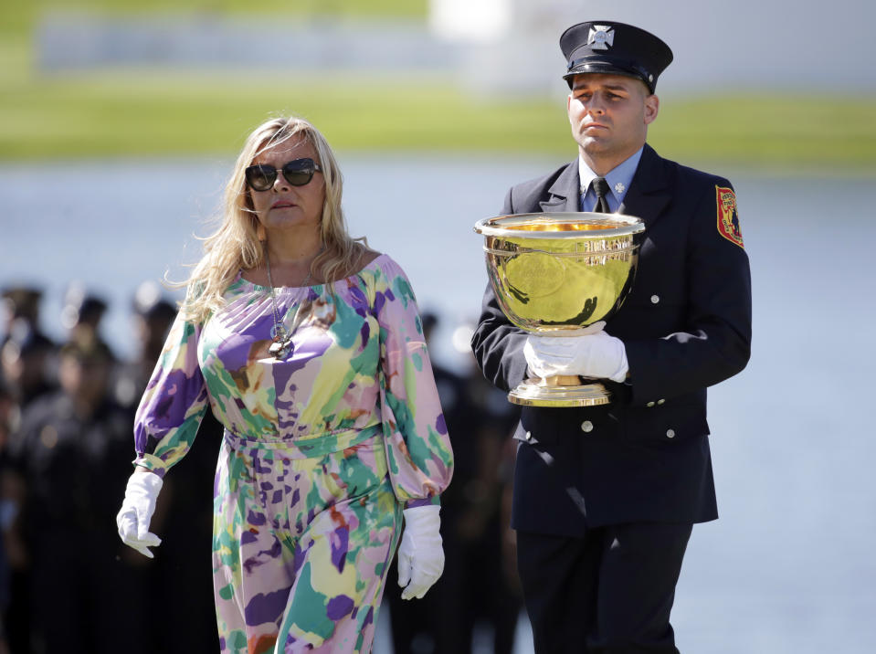 <p>Mark Lee, Jr, right, and Cheryl Lee, left, present the Presidents Cup during the opening ceremony before the first round of the Presidents Cup at Liberty National Golf Club in Jersey City, N.J., Sept. 28, 2017. They were honoring the memory of Jersey City Captain Mark Lee, Sr., who died from health problems believed from working at Ground Zero after the 9/11 terrorist attacks. (Photo: Julio Cortez/AP) </p>