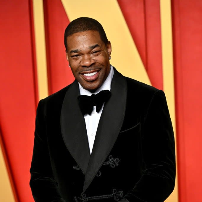 Man in velvet tuxedo with bow tie and pocket square, smiling on red carpet