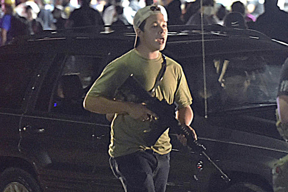 In this Aug. 25, 2020, file photo, Kyle Rittenhouse carries a weapon as he walks along Sheridan Road in Kenosha, Wis., during a night of unrest following the police shooting of Jacob Blake, a Black man. Rittenhouse shot three white men during street protests after the Blake incident. 