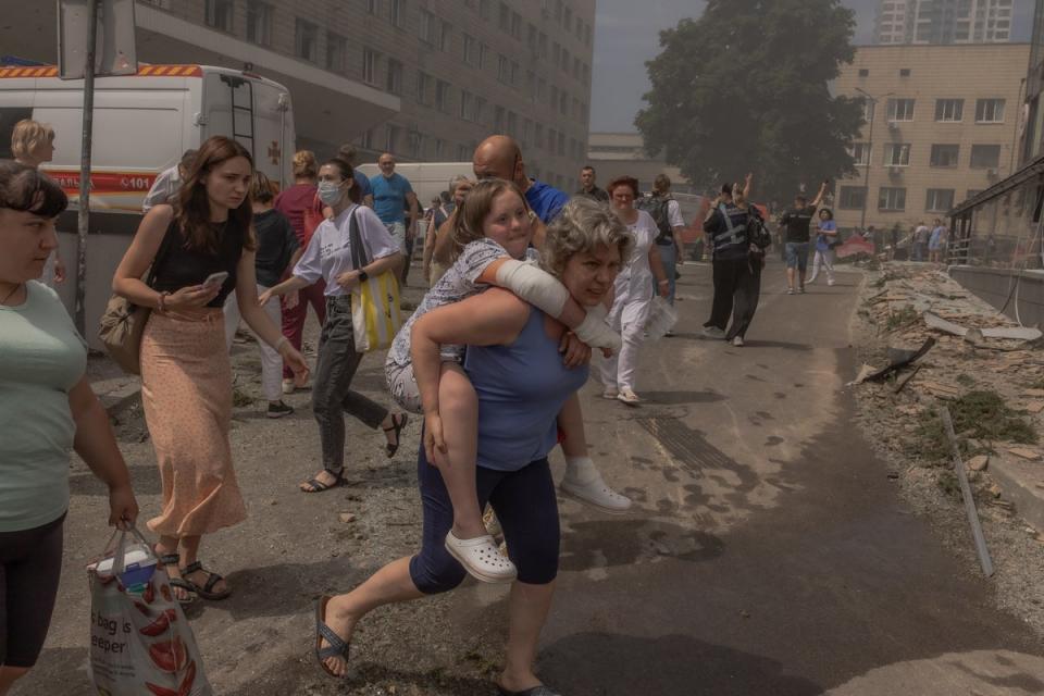 A woman carries a girl from the Ohmatdyt Children’s Hospital in Kyiv (AFP/Getty)