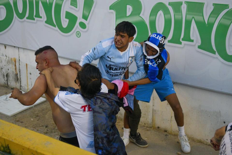 Les fans se battent lors d'un match de football Liga MX entre l'hôte Quer&# xe9;taro et Atlas au stade Corregidora samedi.