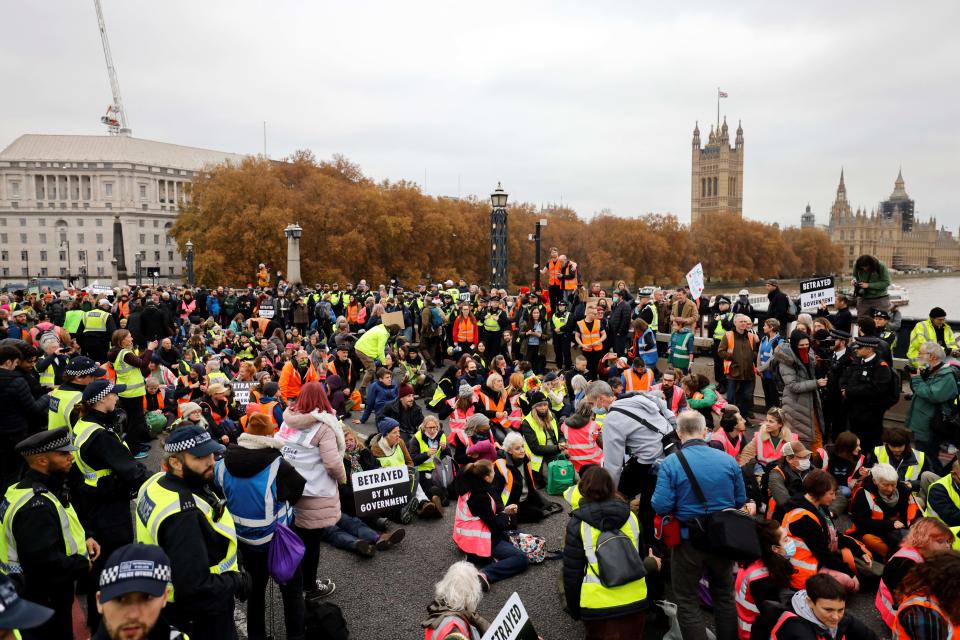 Climate change activists sit down and block traffic during a protest action in solidarity with activists from the Insulate Britain group who received prison terms for blocking roads, on Lambeth Bridge in central London on November 20, 2021. - A British court on November 17, 2021, jailed nine climate change activists who repeatedly blocked roads and motorways, halting rush-hour traffic, after they flouted an order not to protest. (Photo by Tolga Akmen / AFP) (Photo by TOLGA AKMEN/AFP via Getty Images)