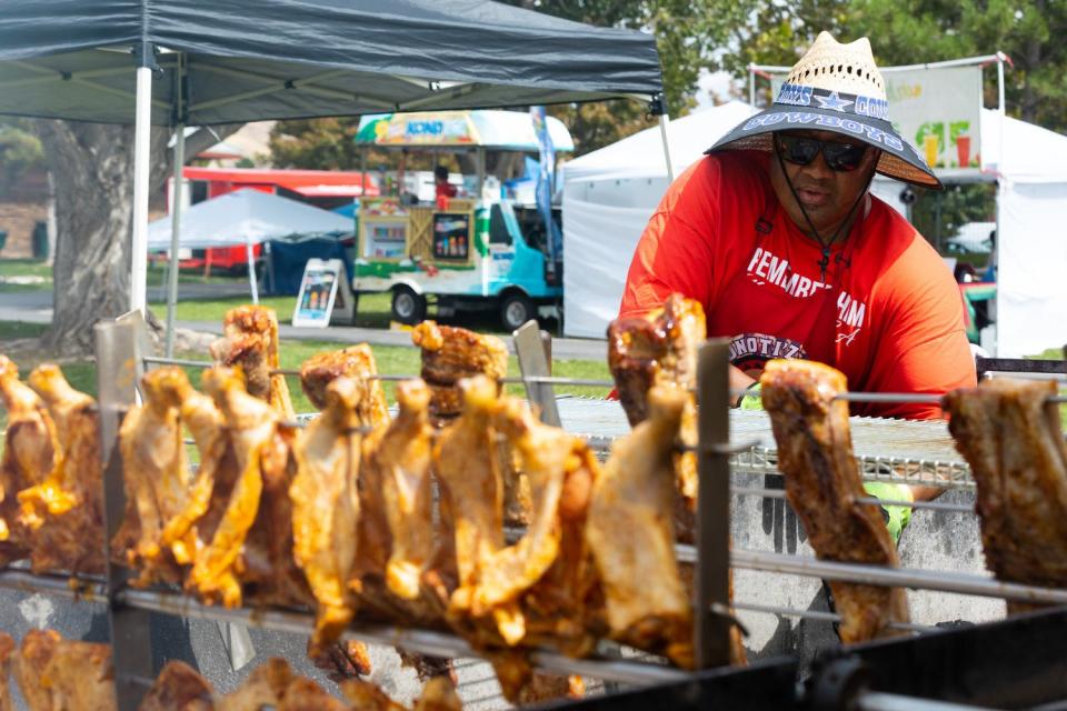 Kiwi Tui tends the coals under the meat at Fonoti’z Fix food truck during Polynesian Days Utah at Electric Park at Thanksgiving Point in Lehi on Saturday.