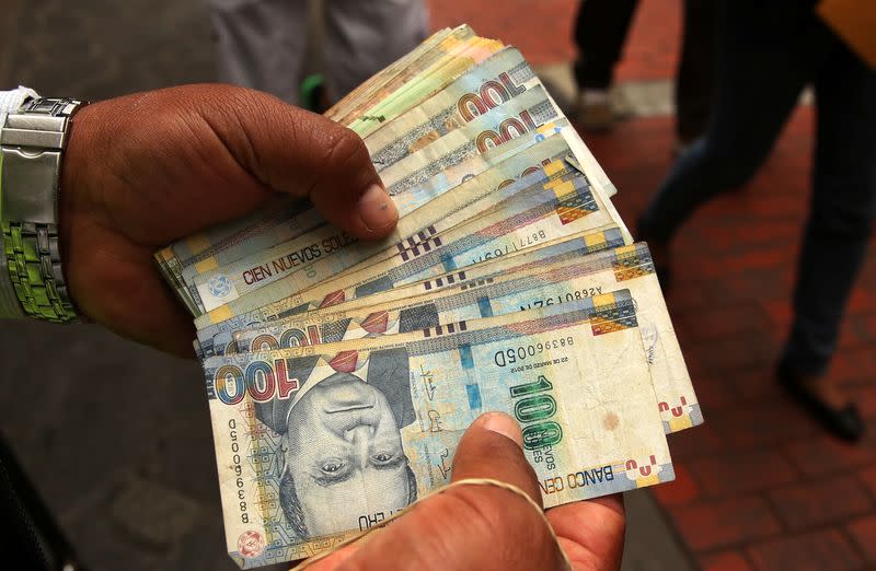 A money changer holds Peruvian Sol bills at a street in downtown Lima