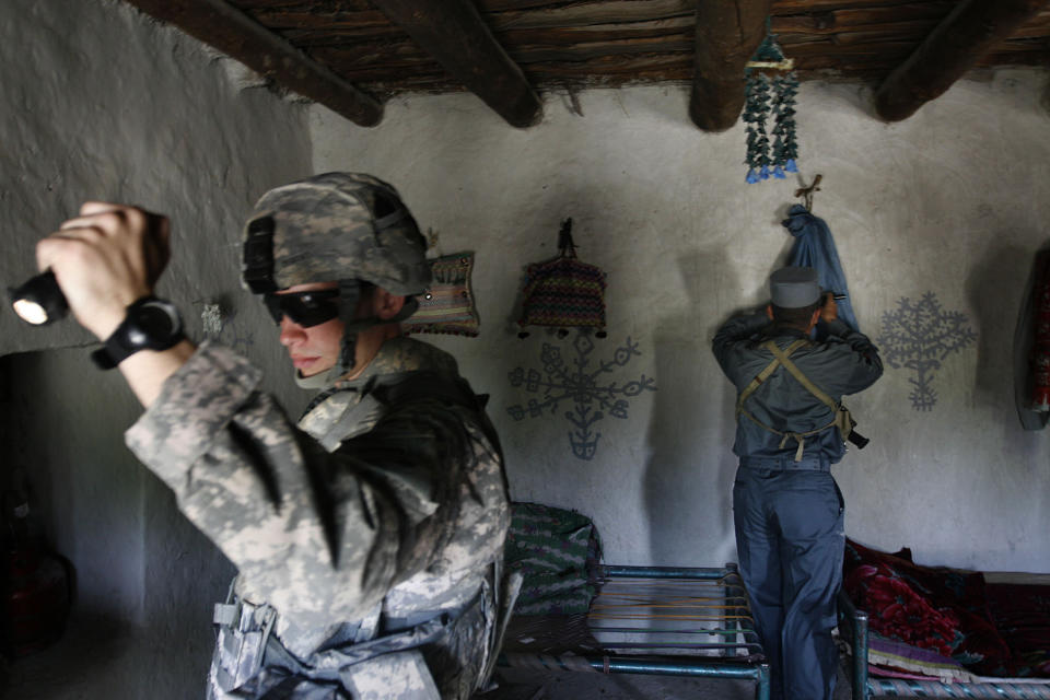 FILE - In this April 18, 2008, file photo, U.S. First Lt. Shane Oravsky, left, of the 101st Airborne Division searches a house with an Afghan police officer in Mandozai, Khost province, Afghanistan. Veterans of America's longest war are torn as the U.S. signs a potentially historic peace accord with the Taliban in Afghanistan. The U.S. signed a peace agreement with Taliban militants on Saturday, Feb. 29, 2020 aimed at bringing an end to 18 years of bloodshed in Afghanistan and allowing U.S. troops to return home from America's longest war. (AP Photo/Rafiq Maqbool, File)