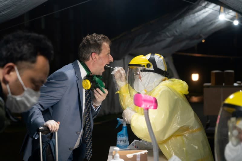 Worker in protective suit collects a throat swab specimen from a passenger coming from Australia for the test of the novel coronavirus that causes COVID-19 in Shanghai