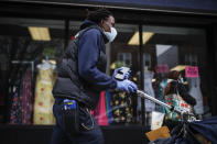 FILE - In this Friday, March 20, 2020 file photo, a postal worker wears a protective mask and gloves while operating a route in the Queens borough of New York. Health experts say the risks are very low that coronavirus will remain on envelopes or packages and infect anyone that comes in contact with it. But those on the frontlines of all those deliveries are taking steps to try to protect themselves. (AP Photo/John Minchillo)