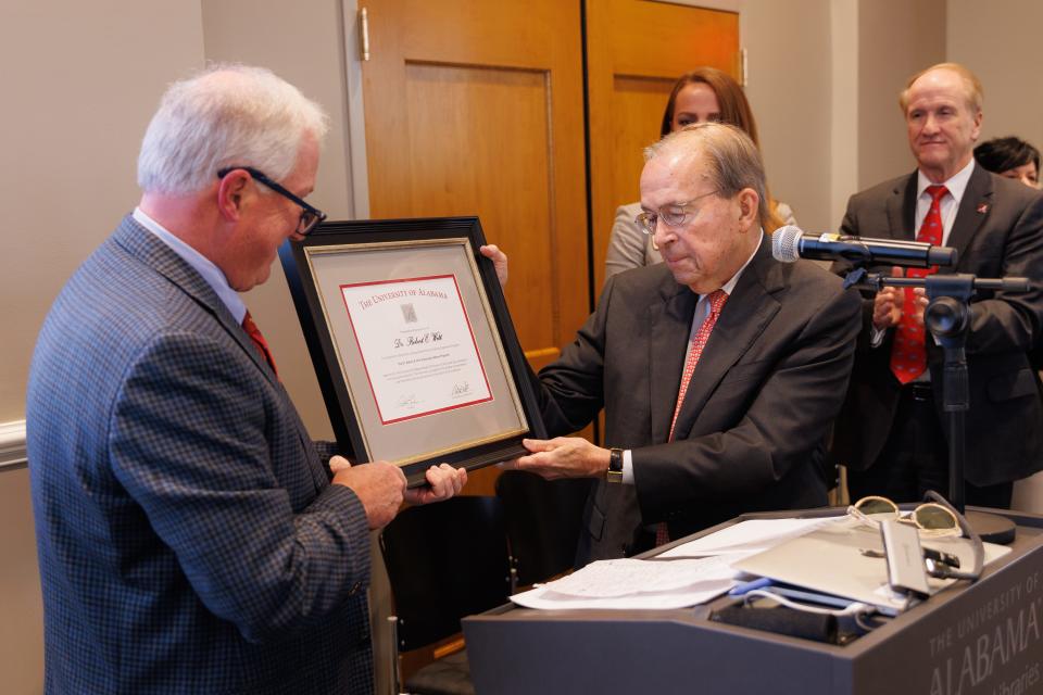 Allen L. Yeilding, chair of the University of Alabama Honors College board of visitors, left, presents a plaque to Robert Witt, UA president emeritus, on Friday in the Camellia Room at the Amelia Gayle Gorgas Library.