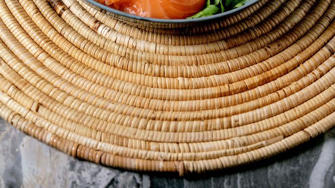 healthy breakfast bowl with fried eggs salmon avocado grilled tomato and salad serving with bread on straw napkin over dark marble background